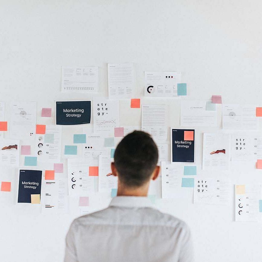 A person standing in front of a wall covered with various notes and business strategy documents.