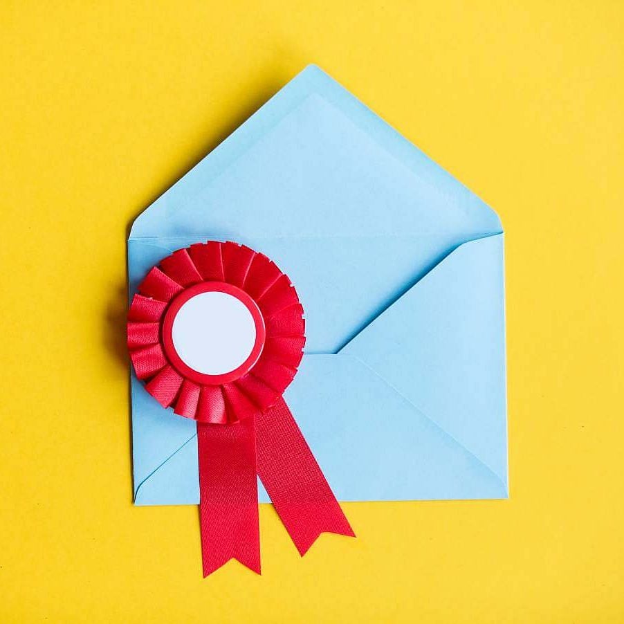 Light blue envelope with a red award ribbon on a yellow background.